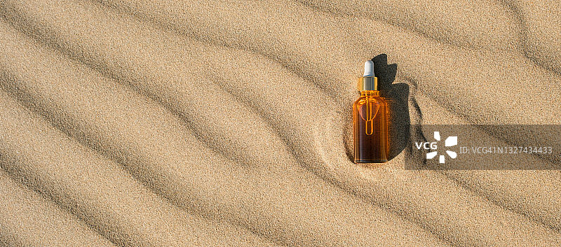 金色橘色防晒油/精华液瓶，沙滩背景，硬阴影，俯视扁平风格图片素材