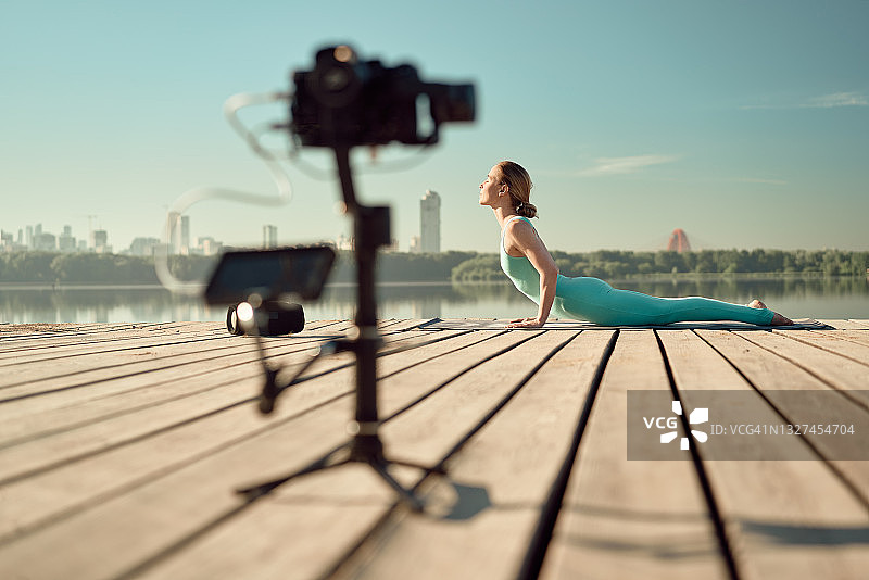 瑜伽女老师在户外练习瑜伽并在线直播图片素材