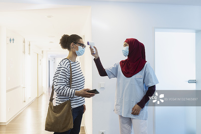 穆斯林女护士使用红外额温计为女性测量体温图片素材