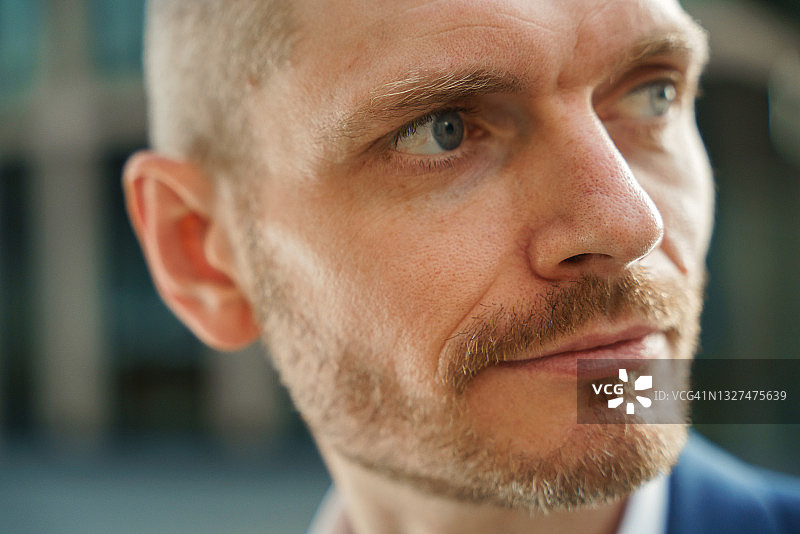 身穿蓝色西装的金发年轻有魅力的男商人特写，看向别处图片素材