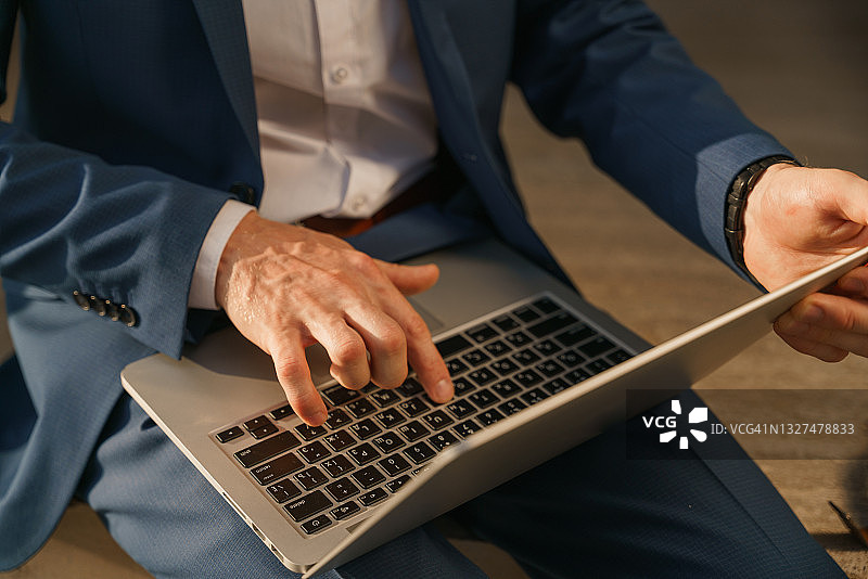 银色笔记本电脑和男人打字的手的高角度视图图片素材