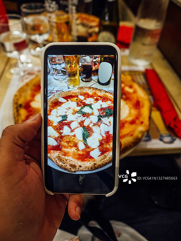 一个男人在意大利那不勒斯的一家餐厅里拍摄他的披萨图片素材