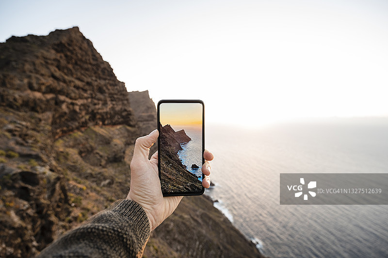 在西班牙大加那利岛日落时拍摄狂野海岸的人图片素材