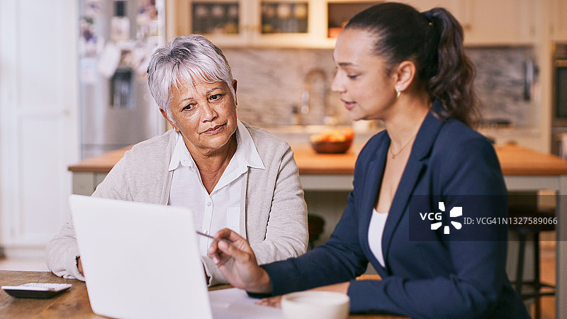老年妇女在家中与顾问开会时使用笔记本电脑的场景图片素材