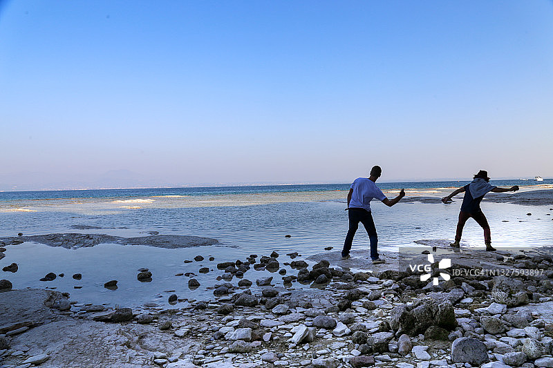 两人在加尔达湖海滩上玩打水漂图片素材