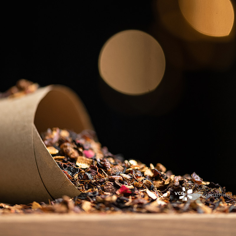 黑色背景上散落着干茶叶，花瓣水果茶和浆果茶，特写镜头，柔焦，留白图片素材