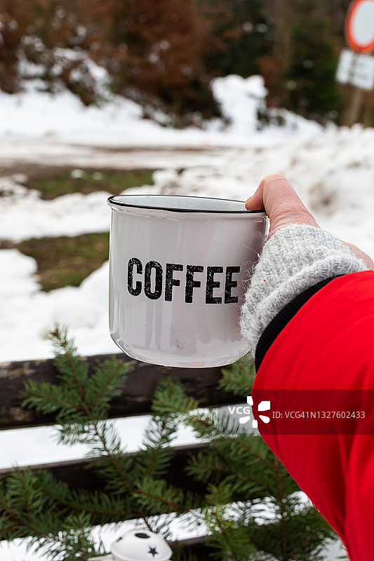 雪地里手捧热咖啡的红衣女人图片素材