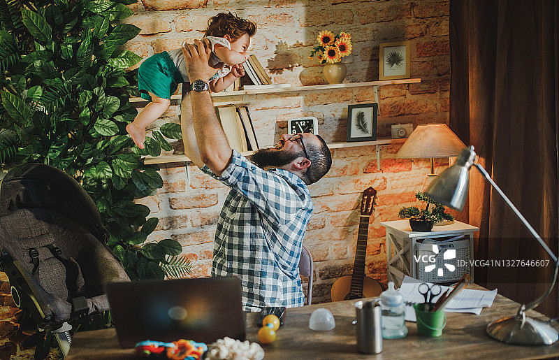 商人抱着他的小儿子在家工作图片素材