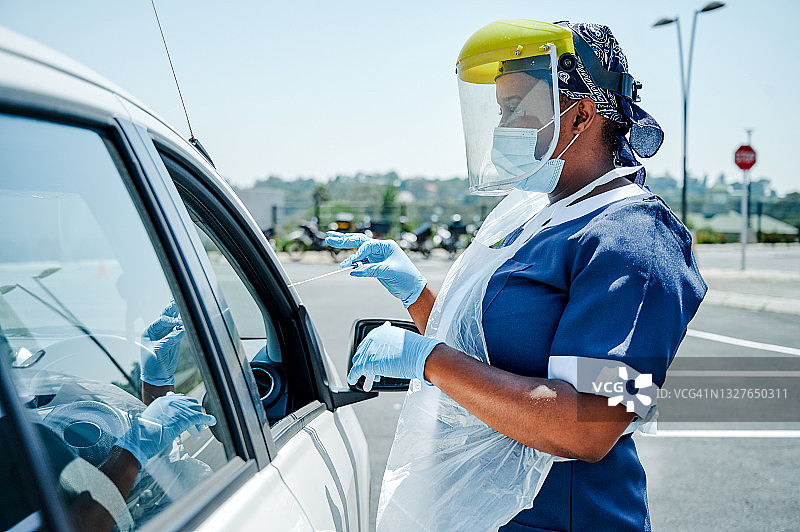 戴着面罩的护士在户外手持棉签图片素材