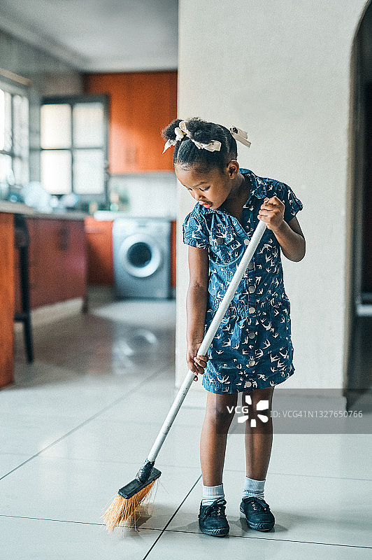 可爱的小女孩在家用扫帚打扫厨房图片素材