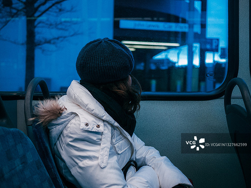 女人坐在公共汽车上，透过窗户向远处望图片素材