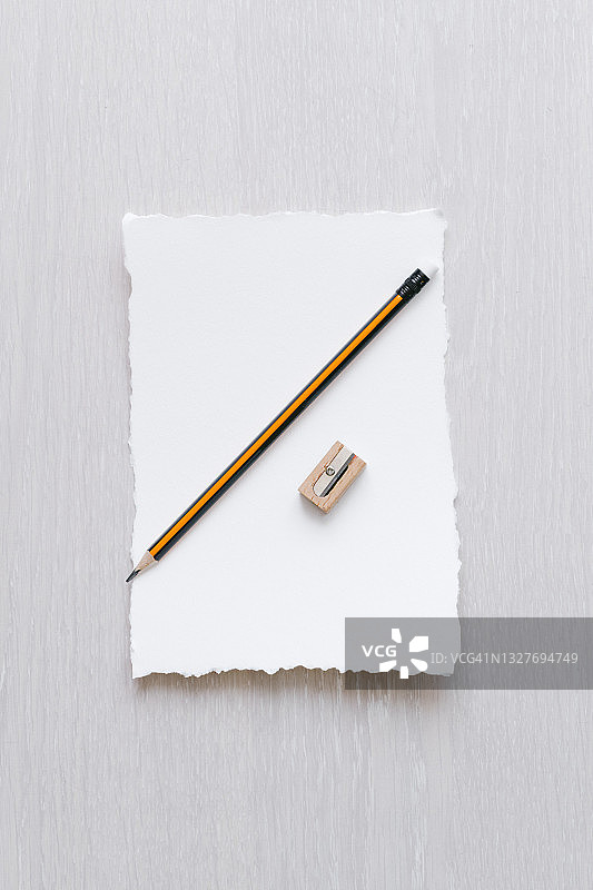 米色背景上的空白纸张、铅笔和木制卷笔刀的简约构图俯视图图片素材