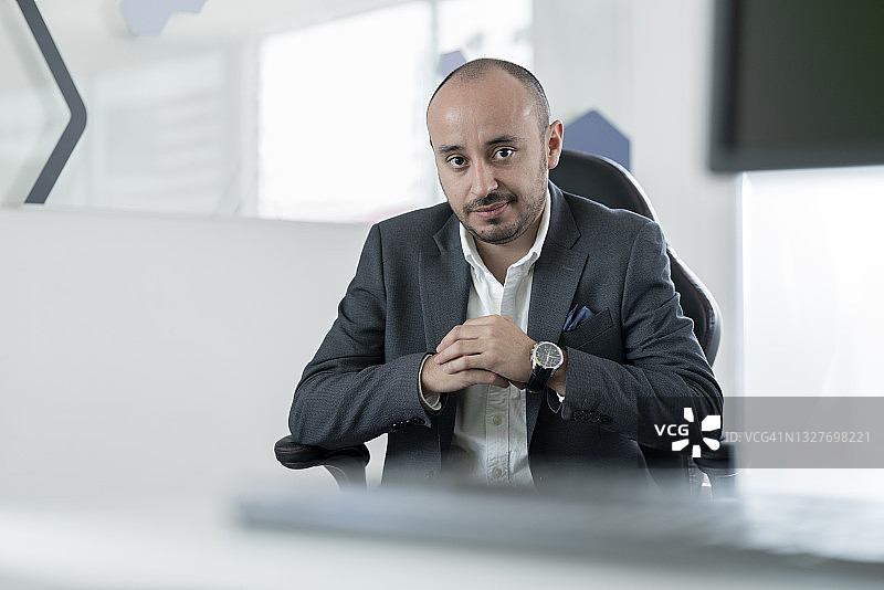 在办公室工作的拉丁裔男人看着镜头图片素材