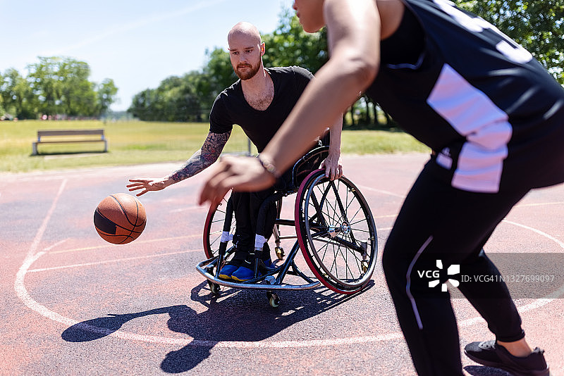 坐在轮椅上与女教练练习篮球的男人图片素材