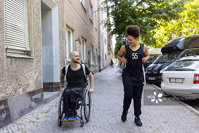 女运动员与轮椅男子在户外同行图片素材