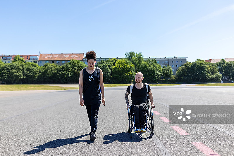 在旧机场跑道上和坐轮椅的男人一起锻炼的女人图片素材