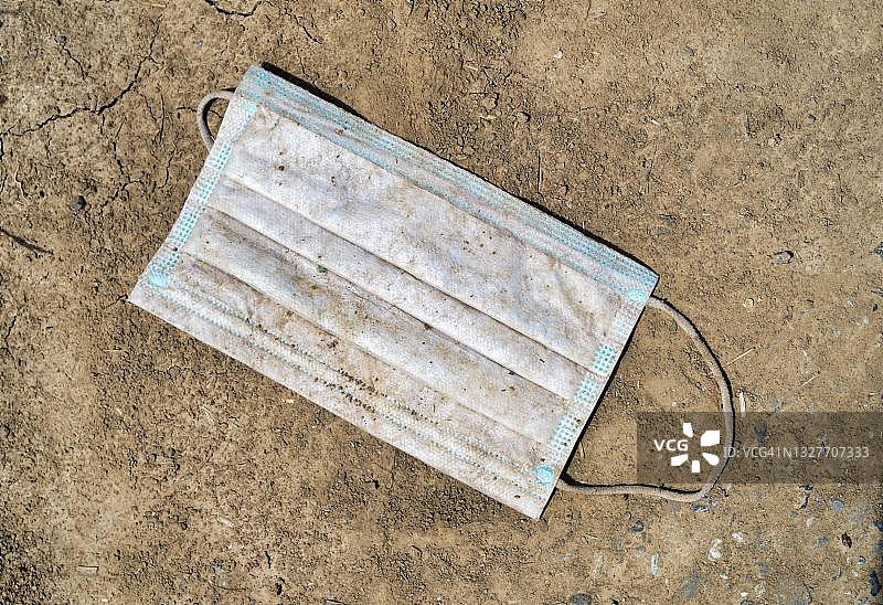 丢弃在泥土中的口罩，象征疫情第三波结束，德国斯图加特图片素材