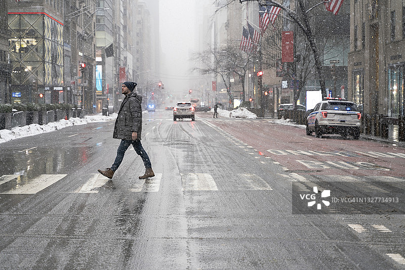 年轻游客在曼哈顿第五大道冒着大雪过马路图片素材