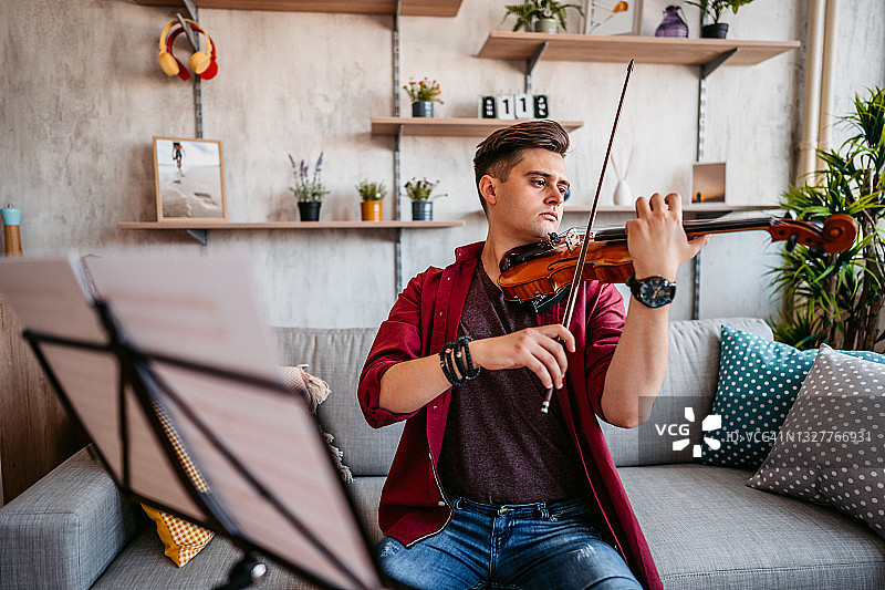 年轻的小提琴手在家练习演奏图片素材