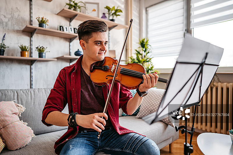 年轻的小提琴手在家练习演奏图片素材