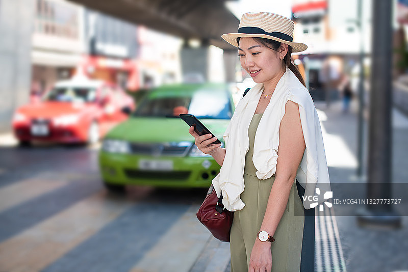 年轻亚洲女性在城市中使用智能手机叫车图片素材
