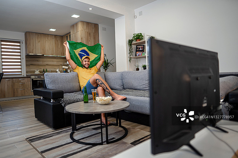 正在看电视体育比赛的年轻男子图片素材