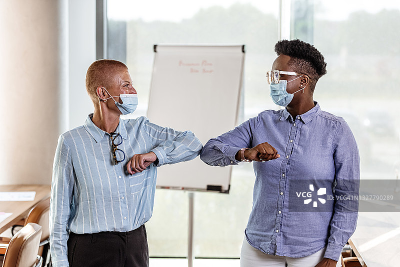 疫情期间戴口罩的商务同事用手肘打招呼图片素材