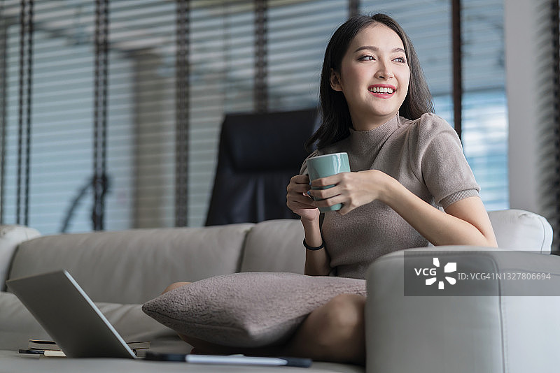 年轻亚裔女子居家沙发放松看笔记本电脑电影图片素材