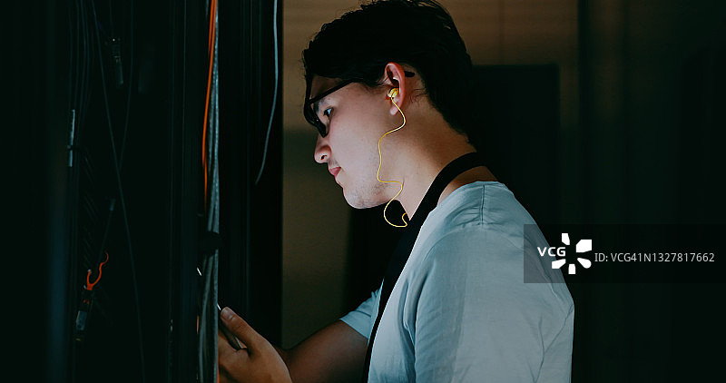 年轻男子在服务器机房工作时使用耳机的镜头图片素材