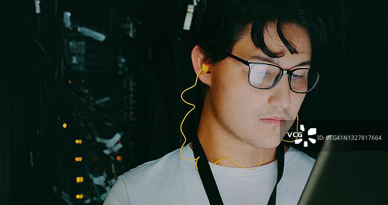 年轻男子在服务器机房工作时使用耳机的镜头图片素材