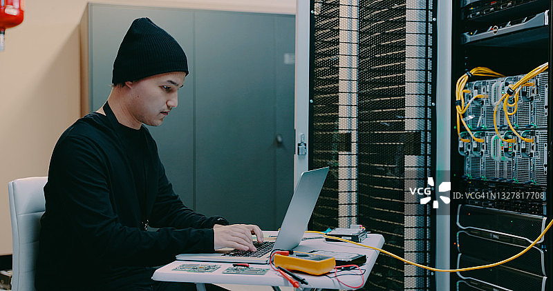 技术员在服务器机房里使用笔记本电脑工作图片素材
