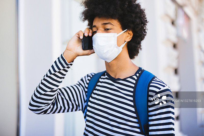 戴口罩的学生使用智能手机图片素材