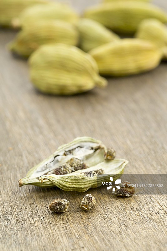 木板上的小豆蔻籽，背景是小豆蔻豆荚图片素材