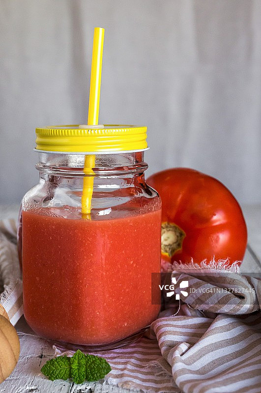 带盖和吸管的螺旋盖罐子里的冰镇番茄汤图片素材
