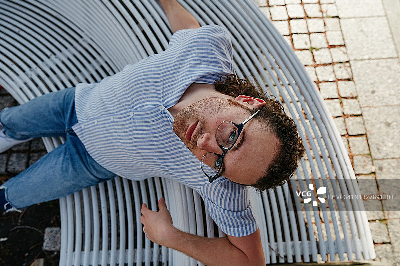 坐在长椅上仰望镜头的年轻男人图片素材