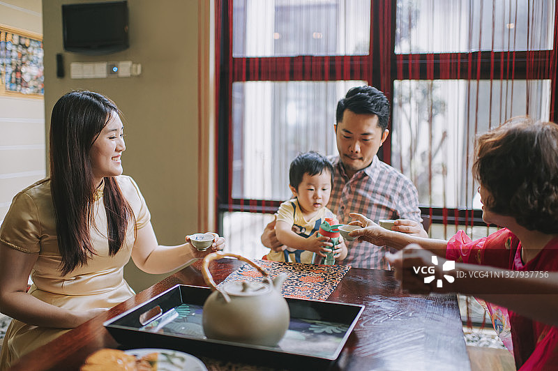 中国多代人在家下午茶聚会，享用传统中秋月饼和中国茶图片素材