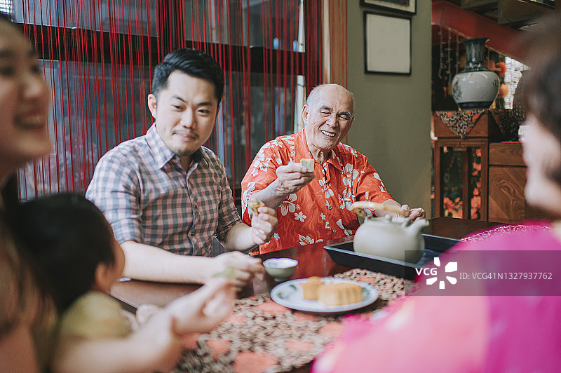 中国多代人在家下午茶聚会，享用传统中秋月饼和中国茶图片素材