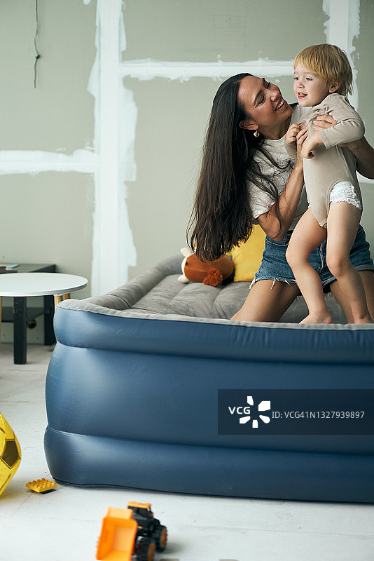 年轻的母亲在充气床上和儿子玩耍图片素材
