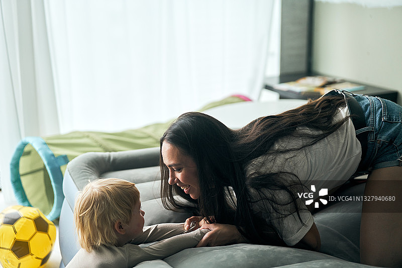 年轻的母亲和儿子在充气床上玩耍图片素材