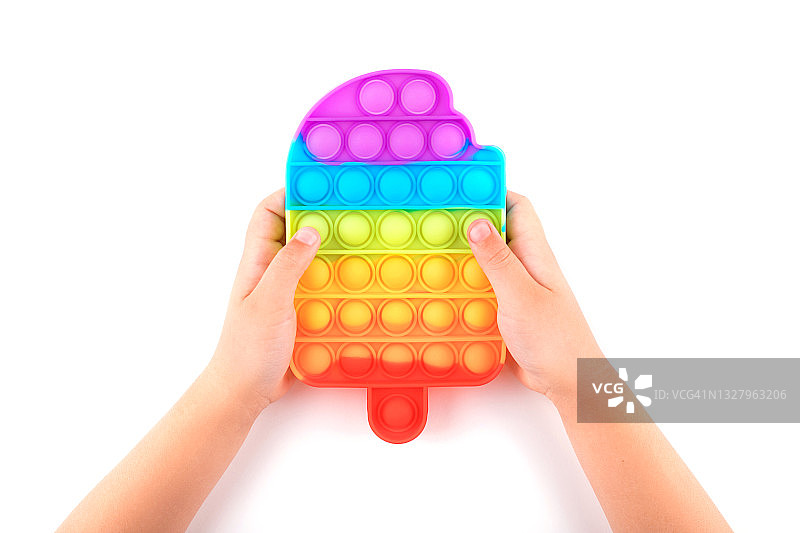 孩子的手拿着彩虹色按压式解压玩具图片素材