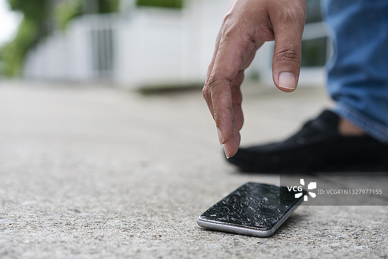 男人将智能手机掉在路上图片素材