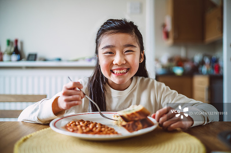 早上在家享用早餐时对着镜头快乐微笑的开朗女孩图片素材