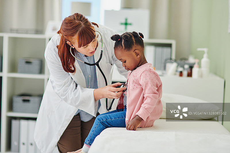 医生用听诊器检查可爱小女孩图片素材