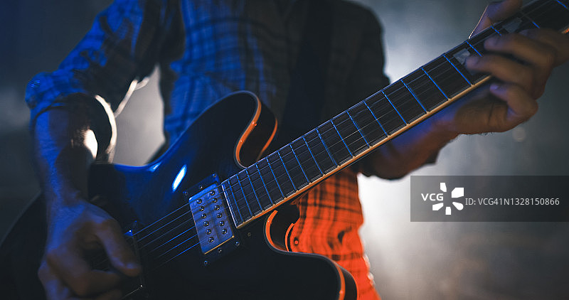 摇滚吉他手在现场演出中演奏吉他，舞台灯光闪耀图片素材