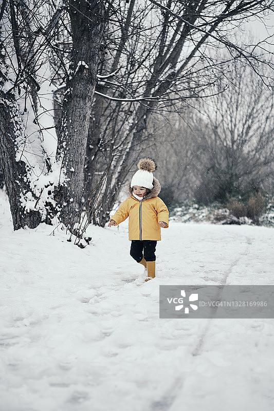 身穿黄色外套的2岁女孩在雪地里图片素材