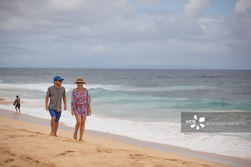 拉丁裔女人和儿子在瓦胡岛沙滩散步图片素材