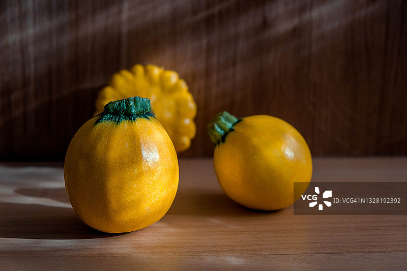 木桌上成熟的黄色西葫芦和盘状南瓜图片素材