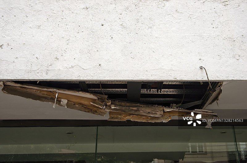 暴雨损坏石膏板店顶篷，暴露电线和钢带图片素材