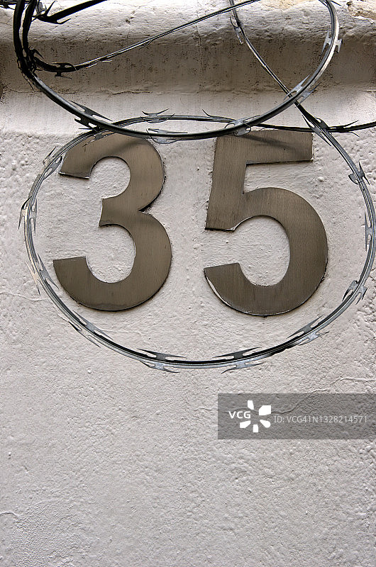 建筑外墙上，被铁丝网环绕的不锈钢门牌号码35图片素材