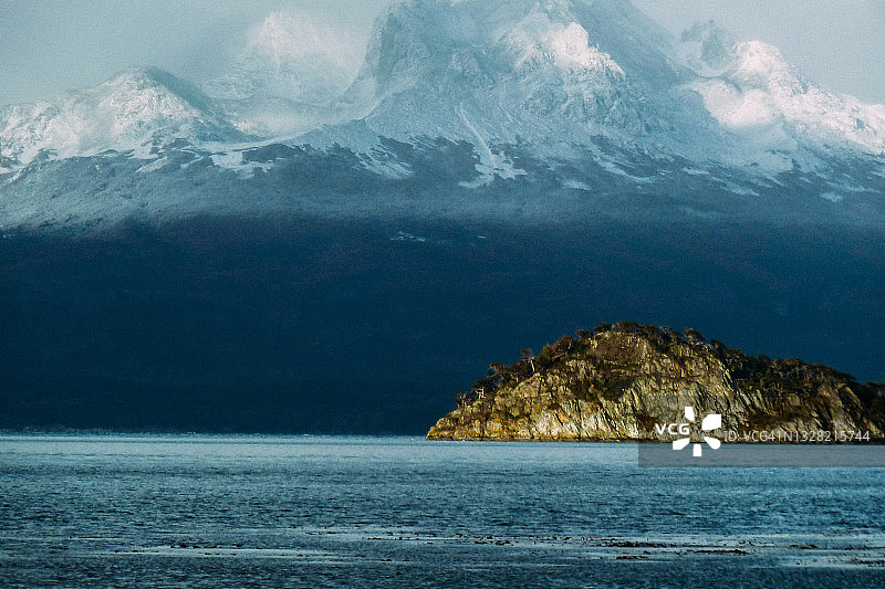 海洋中的岛屿的风景，背景是白雪皑皑的山脉图片素材